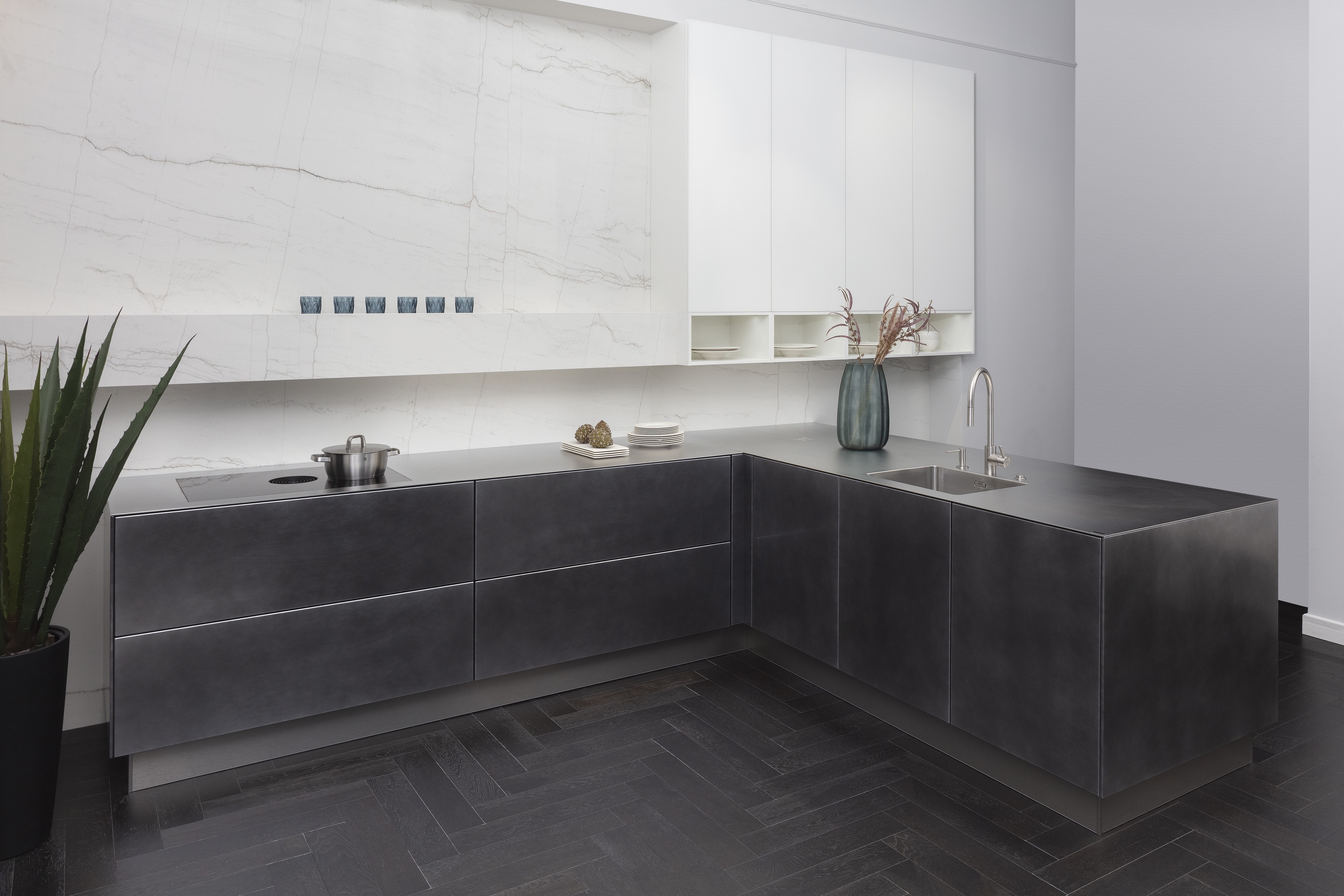 Front: Industriestahl Metalliclack geschliffen AV6000 NCS Mattlack APL: Franke Edelstahl 6 mm Geräte: Bora Spüle Armaturen: Franke  Features: Metallfront, Spülbecken in APL integriert (aus einem Guss), Oberschränke mit Lowboard-Charakter, integrierter Arbeitsplatz, dunkler Korpus mit Aluminium-Abschlussleiste, Wärmeschublade mit Gittereinsatz.